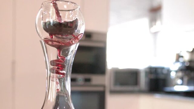 Red Wine Pouring Through Aerator Into Glass Decanter in Modern Kitchen