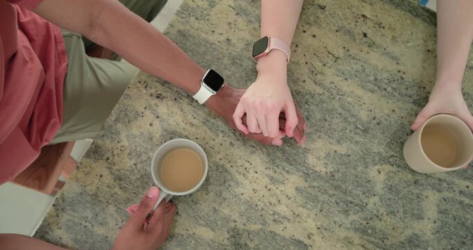 Right person nudging mug, two partners are interlocking hands on granite counter, sharing comfort