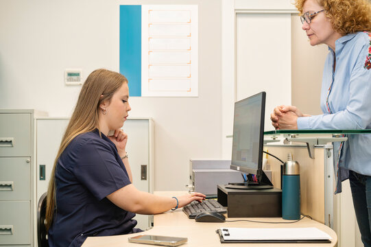 Female dentist interacting with patient while managing information on a computer at the dental clinic front desk