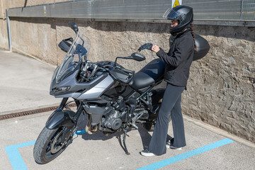 Woman standing beside motorcycle, putting on safety gloves for urban adventure