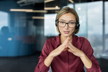 Woman wearing headset and glasses, communicating and discussing during a remote work video...