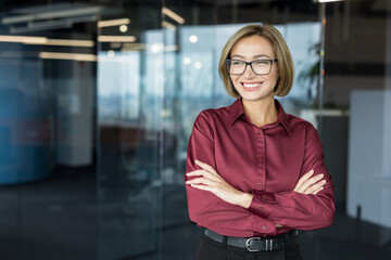 Woman standing in a corporate office setting, showcasing confidence and success, actively engaging...