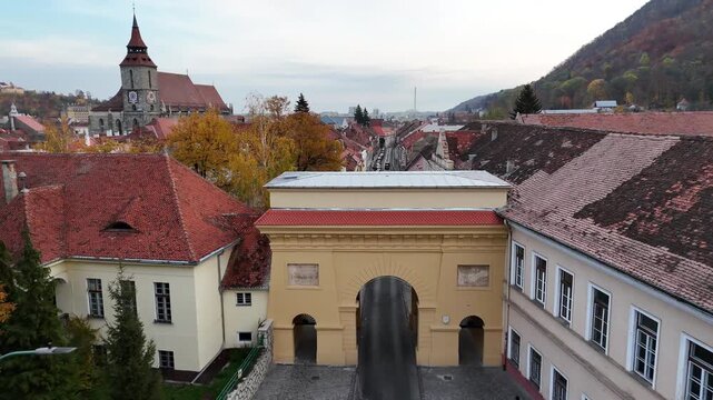 1 november 2024, Brașov, Romania. Forward drone towards and over in Poarta Şchei, Schei gate. Trees with beautiful autumn colors. Beautiful architecture, touristic must-see destination. Black church.