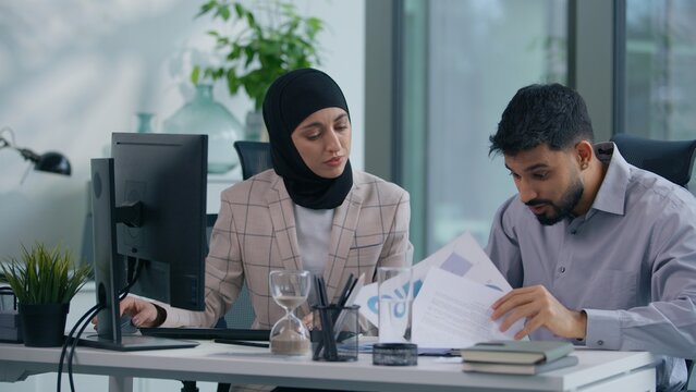 Two muslim business team in office working Islamic group Indian co-workers Arabian colleagues discuss problem bad data information problem difficulty discuss work with computer online startup paper