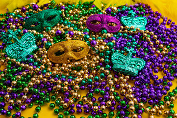 Mardi Gras beads in glittering yellow, green, purple, and gold. Sparkling festive background for Mardi Gras in traditional colors. © Mantas Žiličius