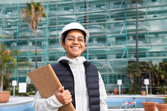 Engineer with safety helmet smiling at construction site outdoors