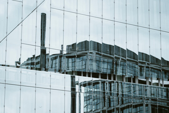 Abstract architecture glass facade with urban reflection pattern on modern building windows capturing rooftop stack silhouette background texture