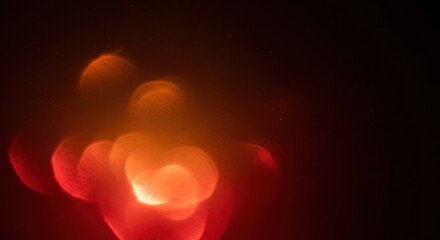 Abstract red and orange bokeh lights with glowing particles on dark background