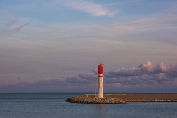 Fototapeta premium White and red lighthouse on a rocky pier at the entrance to Port Vauban in Antibes, French Riviera, France