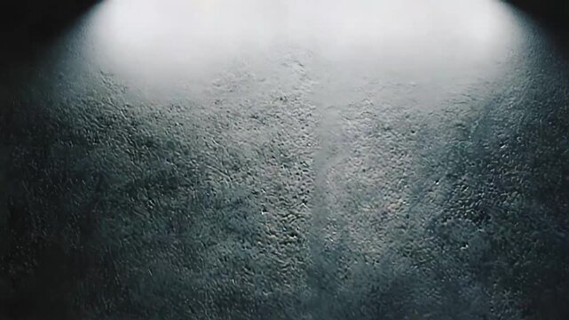 Rough dark gray concrete wall and grungy textured floor forming an empty minimalist studio stage and industrial backdrop with moody light, shadows and ample copy space for product display