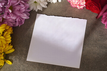 Obraz premium Blank sheet of paper for text or advertisement with background of fresh flowers and natural sunlight