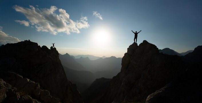 At the summit, two climbers successfully complete a climb at sunrise.