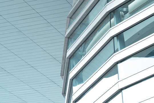 Modern urban architecture facade of glass with crisp lines and grid around a corner creating a minimal pattern and clean office exterior