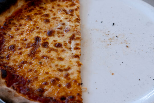 Pizza cheese slice food meal on plate with crust baked closeup and crumbs from a half eaten dinner photographed for appetizing menu use