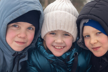 A close-up portrait of two brothers and a sister in winter. The concept of happiness, childhood and family