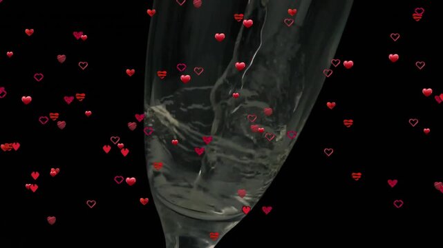 Champagne flute being filled with sparkling wine on black backdrop, with floating red heart icons
