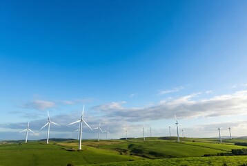 Wind turbines on a green hill under a blue sky, concept of clean energy and sustainable power generation