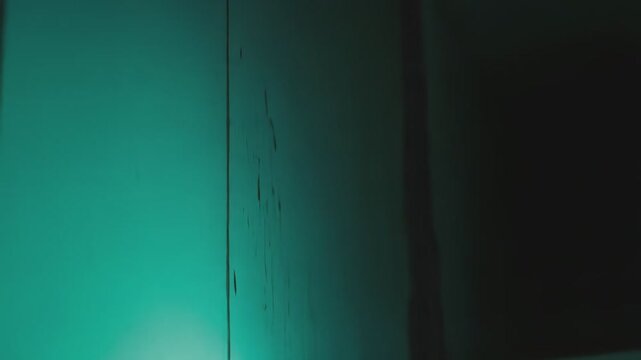 Textured greenish blue wall featuring an uneven surface and areas of apparent moisture damage, creating a grunge background with a dark, moody aesthetic