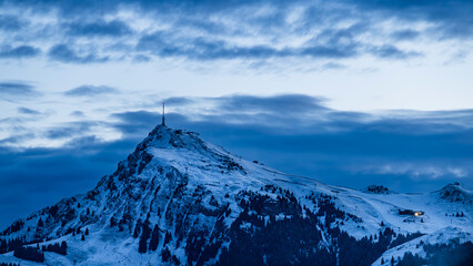 Naklejka premium Snow Covered Alpine Peak at Blue Hour with Dramatic Clouds