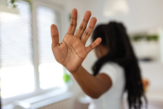 Hand of a Black woman showing stop gesture, expressing refusal and setting boundaries. Concept of saying no, harassment prevention, and personal space on a grey background.