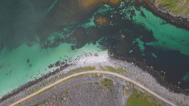 A Narrow Bicycle Path Curves Along a Small Beach Beside Clear Turquoise Water Near Hauklandstranda, Lofoten, Norway - Aerial Topdown Shot