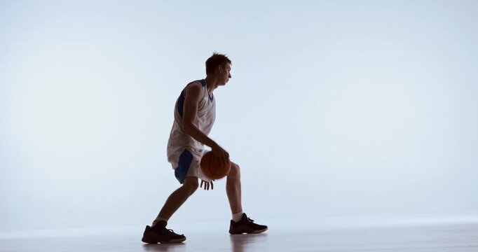 Basketball athlete catching and bouncing ball during focused training moment. Concept of reaction practice, coordination development, agile movement, and skill oriented sports sessions.