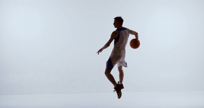 Basketball athlete executing mid air directional turn holding ball behind body. Concept of tactical movement, play breakdown, offensive creativity, and sports education visuals.