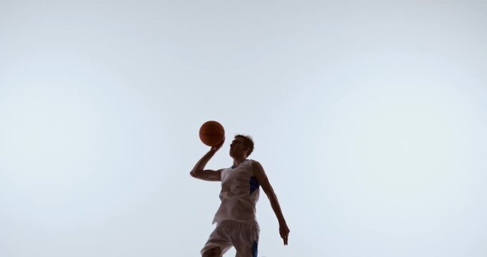 Basketball player extending arm sideways holding ball in wide athletic pose. Concept of athletic form breakdown, agility training, performance promotion, and movement education.