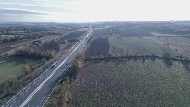 Aerial forward flyover of a busy highway with trucks and cars, France