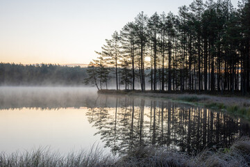 sunset landscape by the lake, beautiful reflection of the lake shore and trees, sunrise colors in the sky, peace and quiet, nobody, autumn