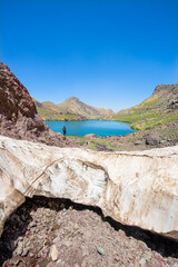 A lake in the mountains, natural scenery, green meadows, snow-capped mountains, blue sky, winter season. Lake views in bloom in spring. Hakkari Cilo Sat Lakes. A lake view in the mountains. 