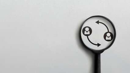 A magnifying glass focuses on icons of two people with circular arrows, symbolizing teamwork,...