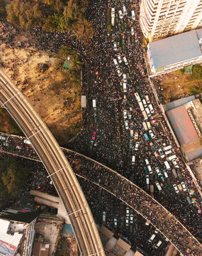 Dhaka, Bangladesh - 31 December 2025: Aerial view of a throng of people filling the streets, contrasting with the stark lines of a modern elevated train track.