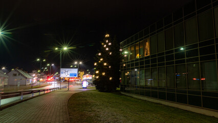 Obraz premium gorgeously decorated city in a Christmas mood, various lights and decorations, decorated facades of houses and fir trees, night landscape