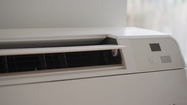 White air conditioner unit switching off. Digital display showing temperature turns dark after beep audio. Horizontal vent closes. Indoor climate control system shutting down at home.