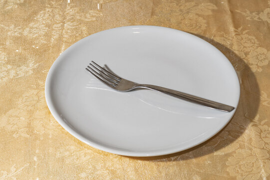 Piatto piano bianco con forchetta d&rsquo;acciaio