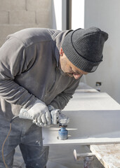 Man drilling holes in ceramic tile with using an angle grinder. Craftmen at work, hands closeup