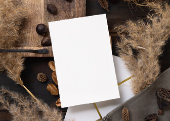 Vertical card on wooden tray near brown decor and pampas grass top view, boho mockup