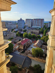 Cityscape. Old buildings with roofs, green trees, road and moving cars on sunny summer evening. Windows and walls of old houses, multi-story buildings in city. City scenery. Urban landscape.