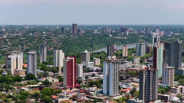 Urban skyline of Foz do Igua&ccedil;u with tall buildings in the foreground and Ciudad del Este visible across the Paran&aacute; River in the distance.