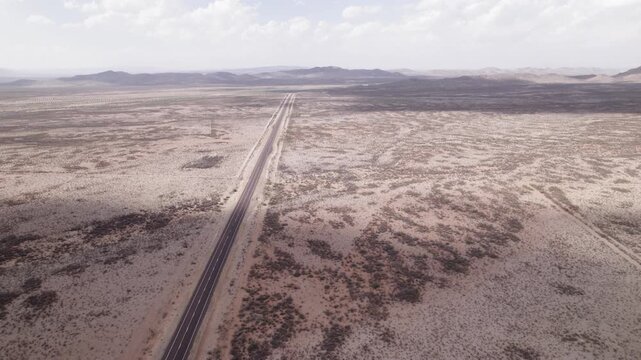 Aerial shot of an empty highway in the west Texas desert, low hills pop out of the horizon