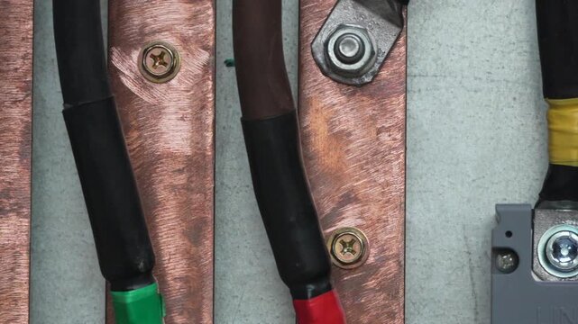 Electrical wiring connections, close up view of copper busbar and cable terminals inside a power distribution box.