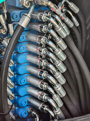 Close view of hydraulic hoses and fittings in machinery at a construction site during daytime operations