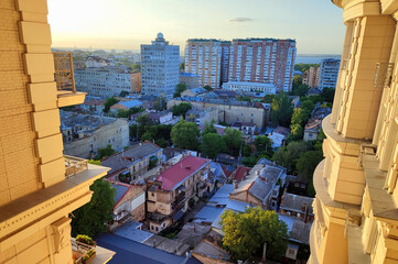 Cityscape. Old buildings with roofs, green trees, road and moving cars on sunny summer evening. Windows and walls of old houses, multi-story buildings in city. City scenery. Urban landscape.