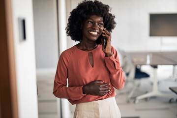 Happy black woman communicating on cell phone in office