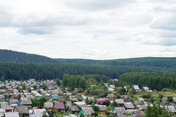 View of rural village with wooden houses and forest hills in summer