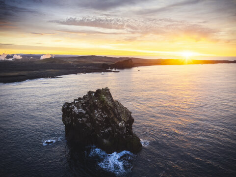 Aerial view of Valahn&Atilde;&ordm;kur cliff piercing the tranquil sea under a radiant sunset, with Reykjanes' rugged coastline in the distance, Keflav&Atilde;&shy;k, Reykjanesb&Atilde;&brvbar;r, Iceland.