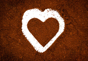 Heart shape carved in ground coffee creating a creative Valentine's Day composition. Romantic concept symbolizing love, warmth, passion, and cozy coffee mood. Top view, close-up.