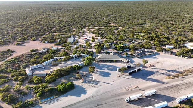 Border Village between South Australia and Western Australia, Eyre Highway, Nullarbor Plain: 4K aerial drone footage of remote roadhouse, boder control, Vehicles, outback highway and vast wilderness