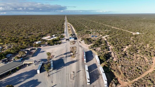 Border Village between South Australia and Western Australia, Eyre Highway, Nullarbor Plain: 4K aerial drone footage of remote roadhouse, boder control, Vehicles, outback highway and vast wilderness
